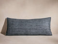 Horizontal dark blue-grey Raw Silk Pillow with visible textured weave and merrow stitch detail, casting shadow on a neutral background.