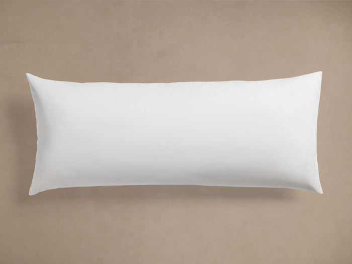 White rectangular Decorative Lumbar Pillow Insert, plump and smooth, centered horizontally on a light brown background.