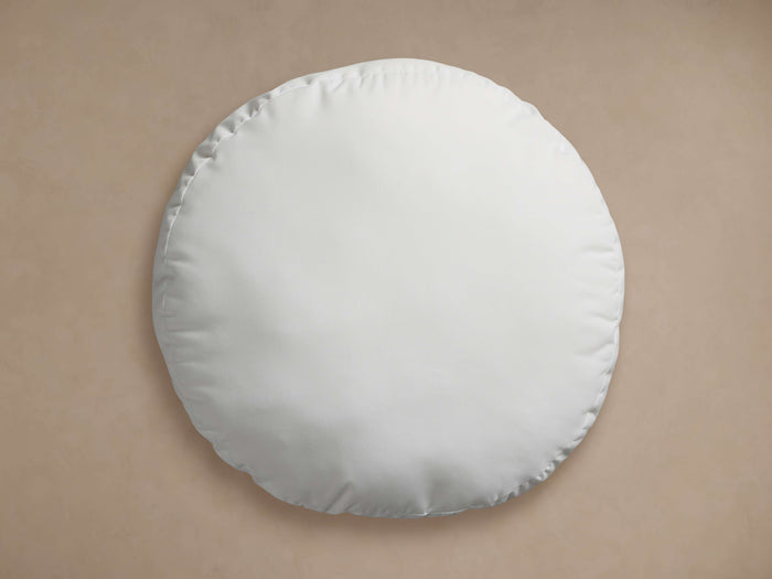A round, white Water Repellent Outdoor Core Insert pillow, looking soft and plump, centered on a light brown background.