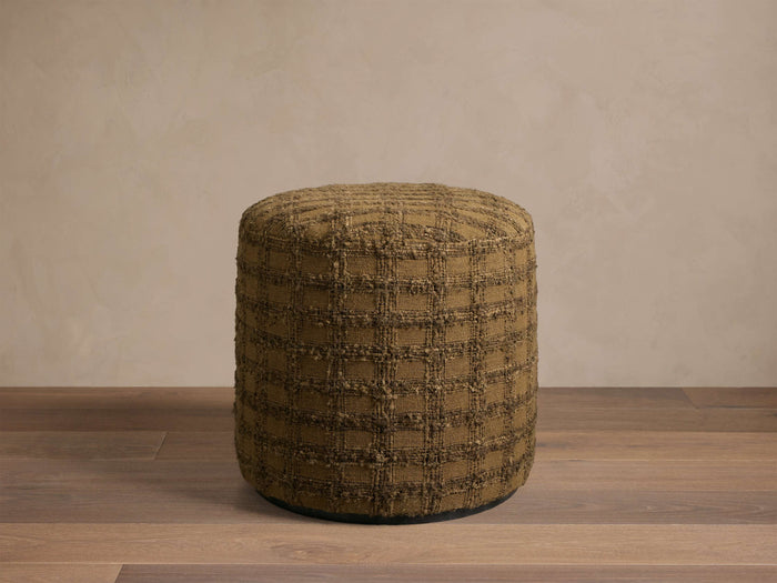 Front view of a round olive brown ottoman with a textured square grid pattern.
