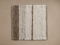Alice Performance Rug Swatch: Cream and brown textured, looped pile swatch with varied striped patterns, laid flat.