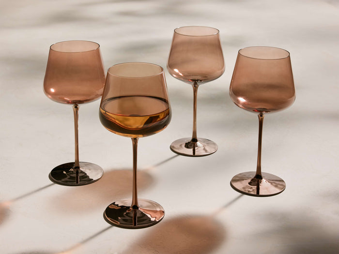 Four Ambretta Wine Glasses (Set of 4) with mocha-smoke glass bowls, metallic bronze stems and bases. One is filled with wine.