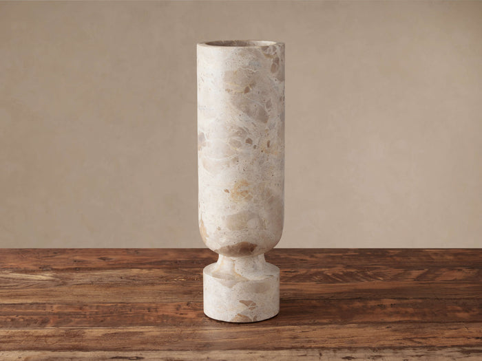 Aphra Vase, a tall natural marble vase with beige and brown veining, standing upright on a rustic wooden table.