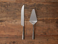 Arber Cake Server set of two, featuring a knife and server with distressed handles, mirror-polished tops on wooden surface.