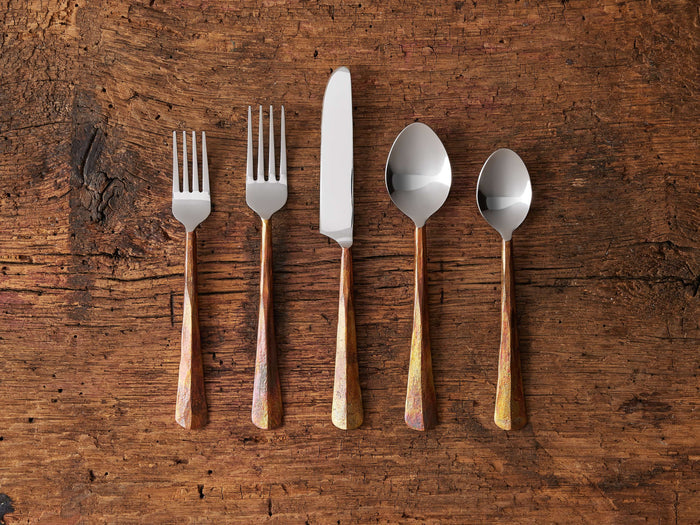 Arber Five Piece Place Setting in Copper on a textured wooden surface. Includes two forks, a knife, and two spoons with distressed handles and polished tops.