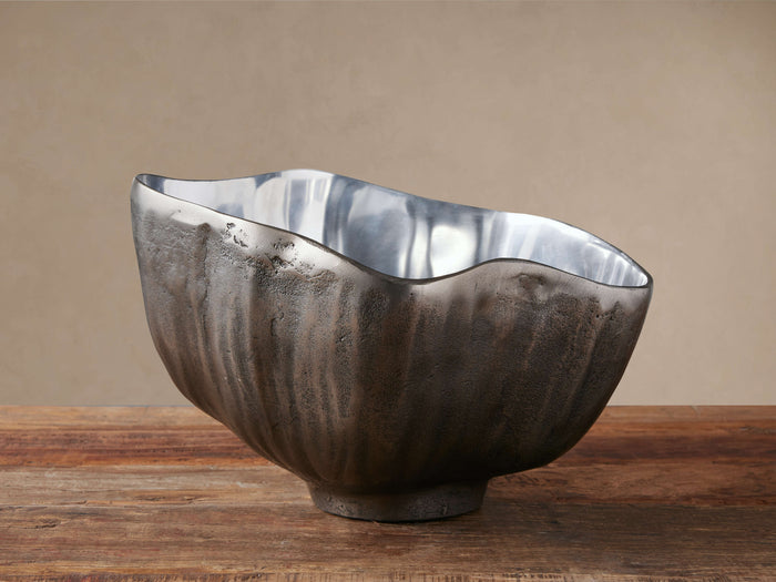 Arber Organic Bowl with a dark, textured exterior and shiny silver interior, sitting on a rustic wooden table.