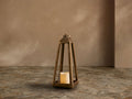Bronze-finished Arc Lantern with a flameless candle inside, on a cobbled floor against a warm taupe wall.