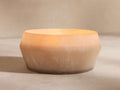 Arhaus Elements Coastline candle in a textured, bowl-shaped frosted glass holder, light beige fading to dark, with a warm glow.