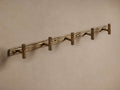 Arren 5-Hook brass coat rack with textured, bark-like backplate and five twig-shaped hooks mounted on a wall.