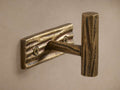 Arren Single Hook, antique brass cast aluminum with tree-bark texture, mounted on a light wall. Visible screws.