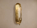 Artemis Wall Taper Candle Holder: Vertical, textured brass sconce with irregular edges, glass cloche, and white taper candle.