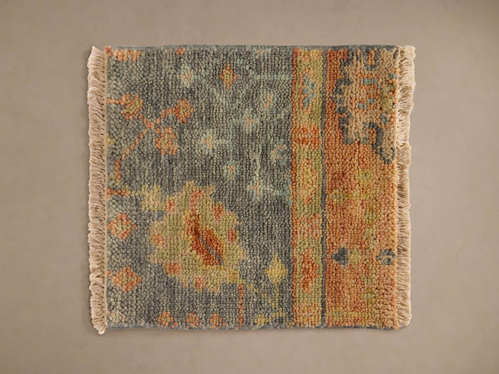 Aspyn Rug Swatch featuring a vintage pattern with blue, orange, yellow hues, and fringe on the sides against a neutral background.