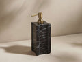 A black marble soap dispenser with natural veining, gold metal pump, and a rectangular shape on a neutral background.