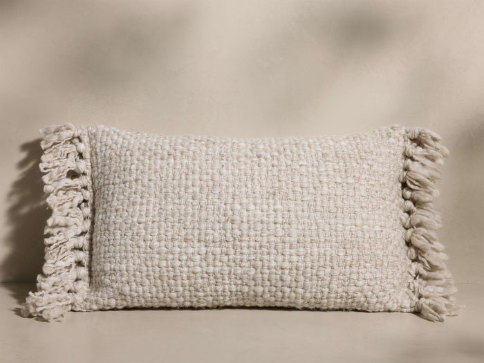 Front view of the cream mélange Audie Pillow, handwoven from merino wool with a basketweave texture and soft fringe on the ends.