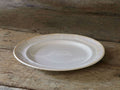Bela Salad Plate, creamy off-white stoneware with glossy, antiqued rim, angled on rustic wood.