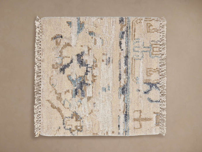 Brielle Hand-Knotted Rug Swatch: Cream colored with abstract light blue, dark blue, and brown patterns, fringe edges, flat.