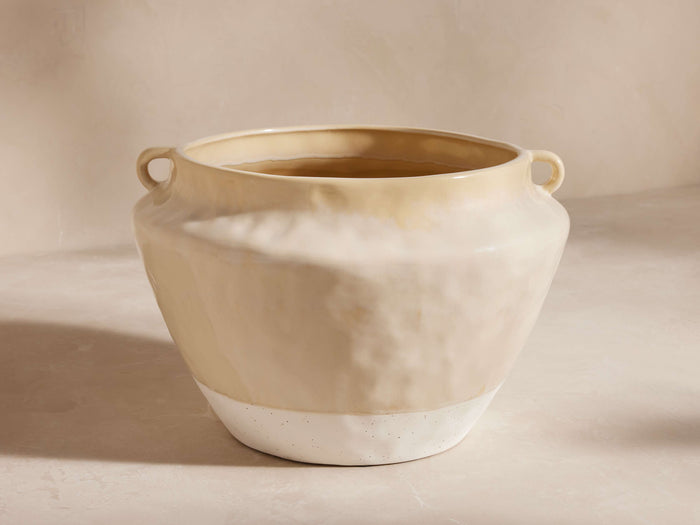 Bronwen Pot, a creamy ceramic pot with a textured, glazed finish, small handles, and a speckled white base, on a light surface.