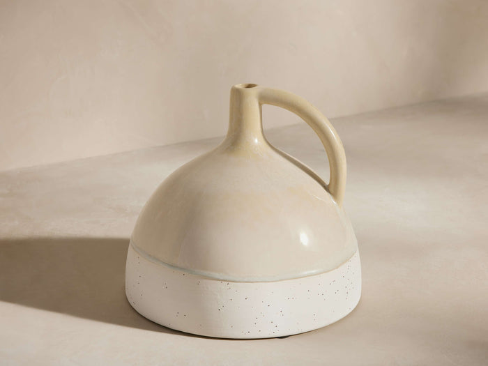 Bronwen ceramic jug vase: Cream glazed top, speckled white matte base. Bell-shaped with narrow neck, single handle.