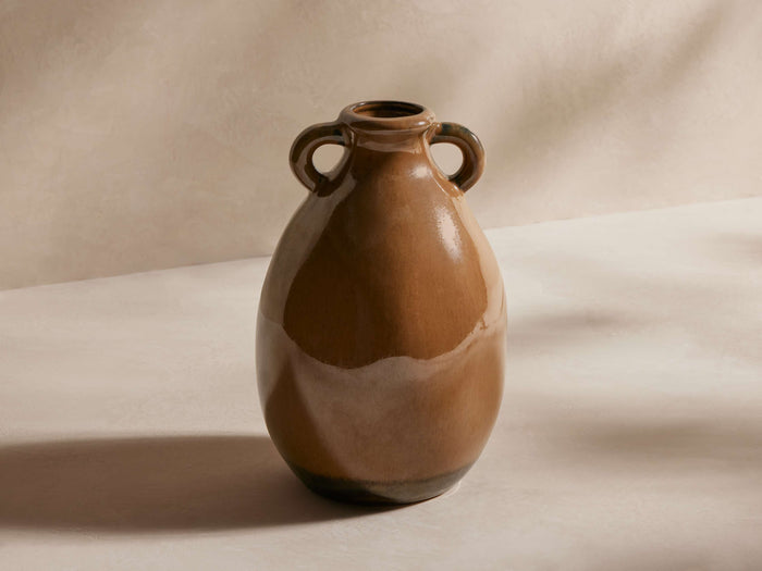 Bronwen Vase in brown tones, with a glossy finish, round body, two small loop handles near the top, on a light surface.
