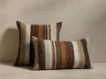 Two Brushtip Pillows: one square, one rectangular, both with vertical jacquard stripes in mocha, ivory, burnt orange, pale blue.