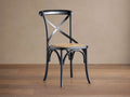 Black Cadence Dining Chair with natural rattan seat. X-back, curved legs, angled on a brown wood floor against a beige wall.