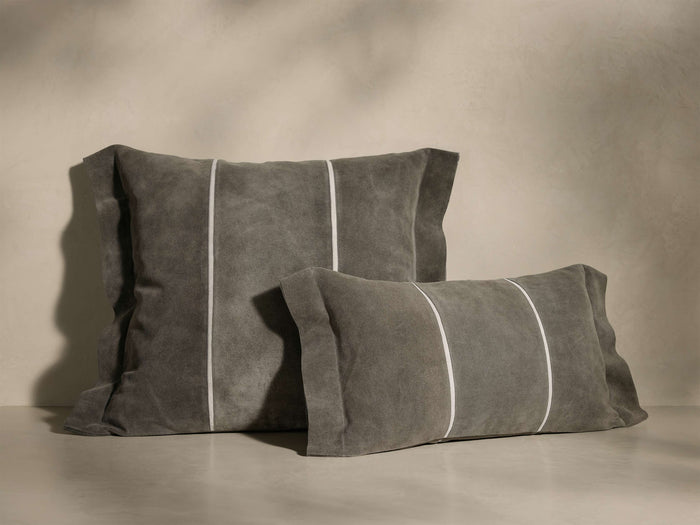 Front view of two gray suede Calais Pillows, one square, one rectangular, with flange edges and white vertical contrast stripes.