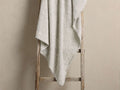 Light gray heathered blanket draped over a rustic wooden ladder, highlighting its soft, fluffy texture.