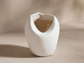 Calixta Bud Vase in matte white ceramic with an organic, asymmetrical shape, featuring a light taupe interior.