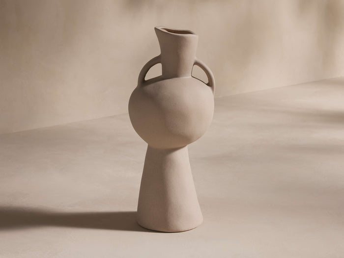 Calixta Vase in light taupe, featuring a matte finish. Vase has a wide, rounded body with two loop handles and a narrow neck.