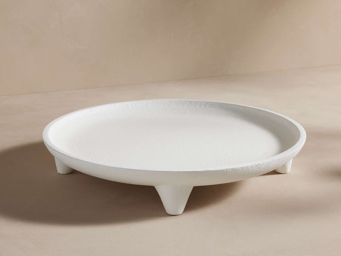 Calliope Round Tray in white with a textured surface, resting on three short legs, displayed on a neutral background.