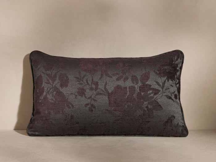 Camellia Lumbar Pillow with a dark floral jacquard motif on a neutral gray background, rectangular shape, placed on a beige surface.