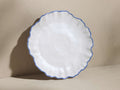 White Capuchos salad plate with a matte finish, scalloped rim, and hand-painted blue edging, slightly tilted on a neutral background.