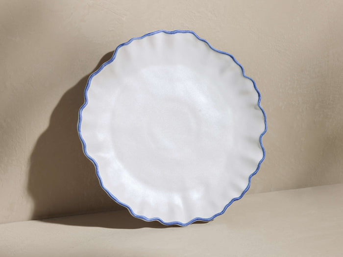 White Capuchos salad plate with a matte finish, scalloped rim, and hand-painted blue edging, slightly tilted on a neutral background.