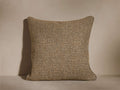 A textured square cushion with a woven pattern in shades of brown and beige, set against a neutral background.