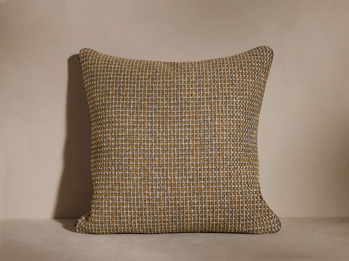 A textured square cushion with a woven pattern in shades of brown and beige, set against a neutral background.