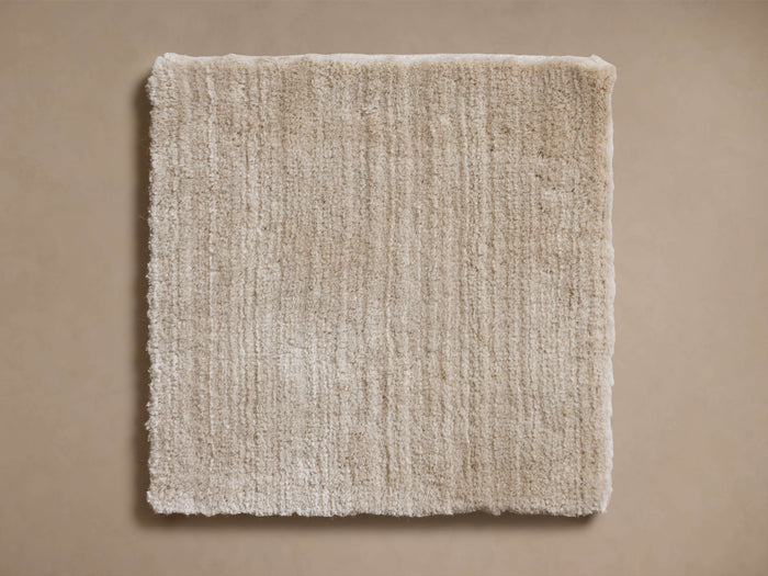 Cashmere Handwoven Rug Swatch in a square shape, featuring a soft beige color and a textured, plush surface on a tan background.