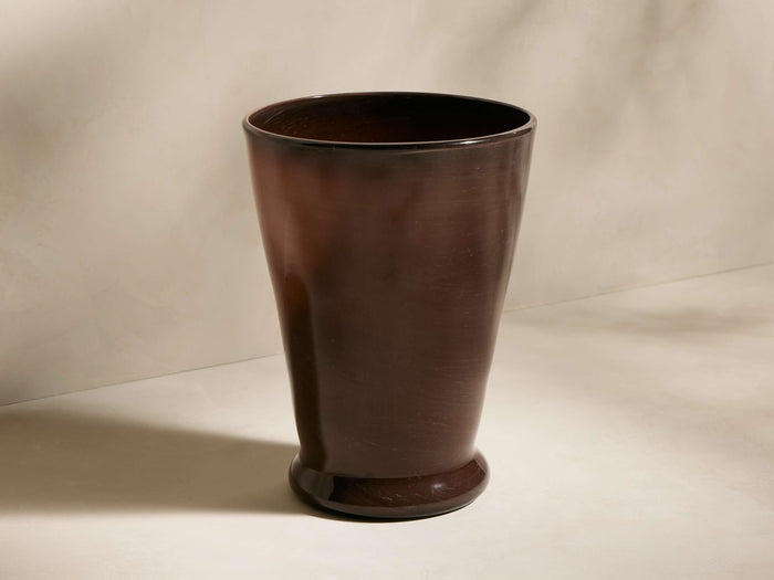 Cassia Vase, a tall, dark brown hand-blown recycled glass vase with a subtle taper and rounded base, standing on a light surface.