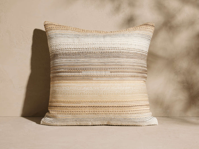 Catia Outdoor Pillow with warm tonal textured horizontal stripes in cream, beige, light gray, and light brown.
