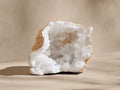 Upright chalcedony mineral geode, split open. Sparkling white crystals fill the interior cavity, surrounded by rough light tan rock.