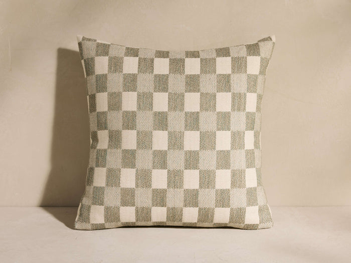 Square Check Pillow with a sage green and cream woven checkerboard pattern, standing upright against a light wall.