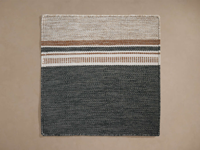Cielo Performance Rug Swatch, rectangular woven fabric. Top half: light beige with horizontal tan, thin black, white stripes. Bottom half: solid dark gray.