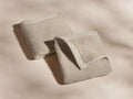 Two beige towels displayed on a smooth surface, one folded neatly, the other slightly unfolded, showing the texture and edges.