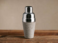Colette Cocktail Shaker, shiny silver stainless steel top with textured light gray hair-on-hide base, on wood.