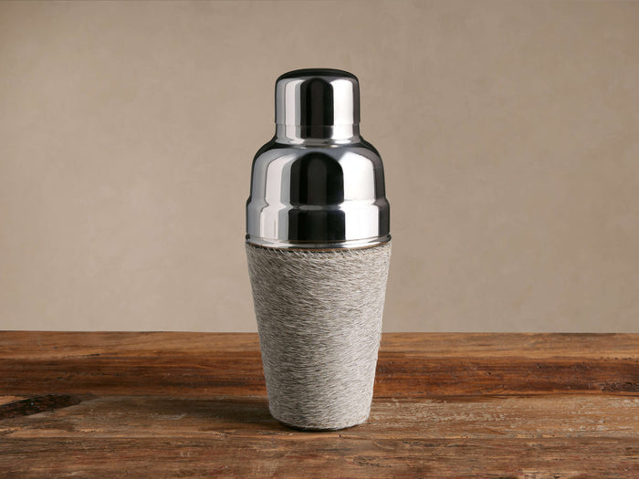 Colette Cocktail Shaker, shiny silver stainless steel top with textured light gray hair-on-hide base, on wood.