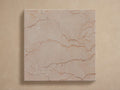Cruz Outdoor Finish Board: Square, light beige/pink marble with reddish-brown veins, centered on a light tan background.