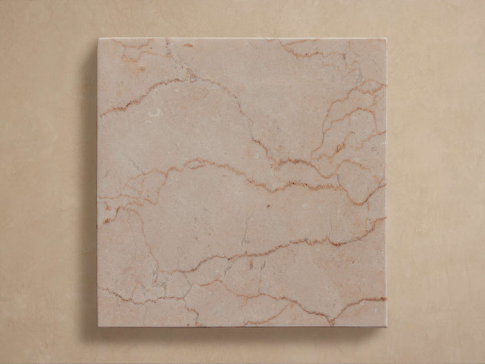 Cruz Outdoor Finish Board: Square, light beige/pink marble with reddish-brown veins, centered on a light tan background.