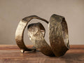 Textured, spiral Curled Sculpture with a distressed antique brass finish, resting on a wooden table.
