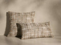 Front view of two Daraja Pillows, one square and one rectangular, featuring a distressed plaid pattern in beige, brown, and cream.