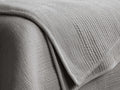 Daria Velvet Quilt, draped in light gray, showing its plush, horizontally quilted texture and soft corded piping.