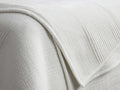 White Daria Velvet Quilt, plush and textured with parallel quilting lines. Folded over, showing corded piping trim.